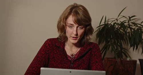 Woman Using Laptop at a Table Indoors