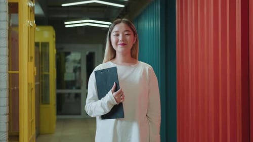 Portrait of a Stylish Asian Business Woman Standing in the Corridor with a Folder of Documents in