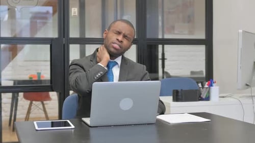 Man in Suit Massaging Neck at Desk