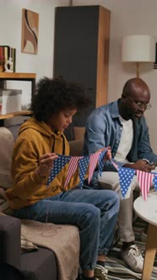 Festive Family Stringing Patriotic Flags Together at Home