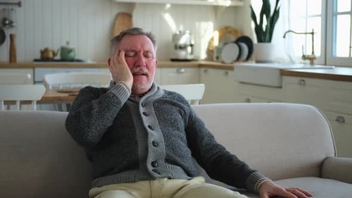 Older Man with Headache on Couch Indoors