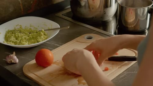Woman Dicing Tomato for Guacamole in Kitchen
