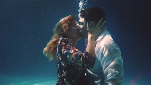 Cinematic shot of young carefree romantic loving couple is kissing with passion in ocean underwate