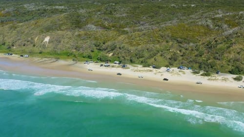 Blue Ocean Waves Beside 4WD Cars Driving Along Sandy Beach Shore, 4K Aerial Drone