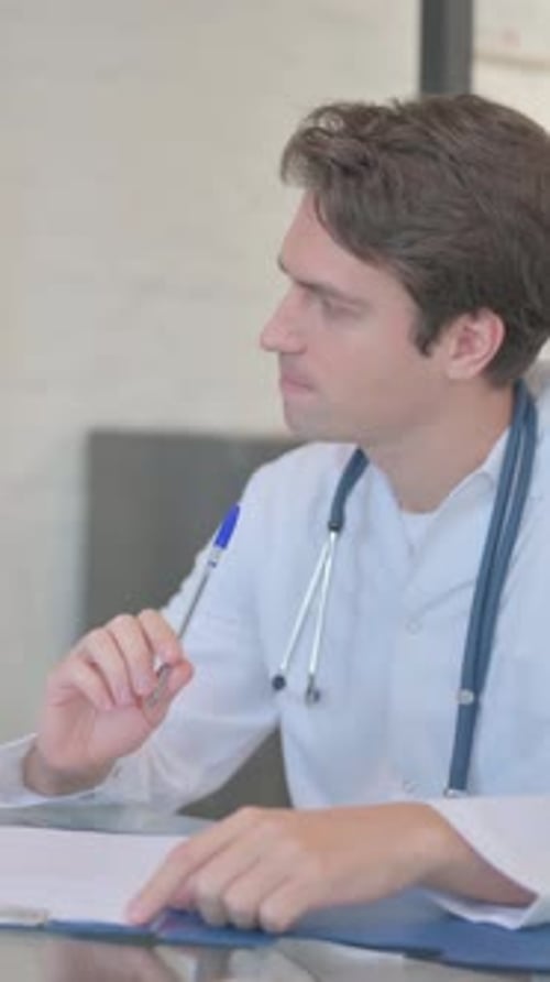 Male Doctor Writing Notes in Hospital Setting