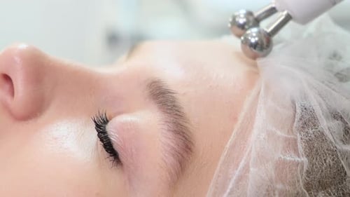 Woman Receives Microcurrent Treatment on Forehead at Salon