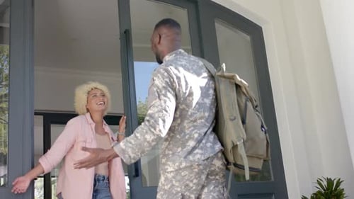 Militar se reúne com o parceiro em casa, abraçando-se em câmera lenta.