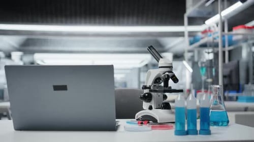 Close Up of Laptop on Laboratory Workbench Next to Microscope and Samples