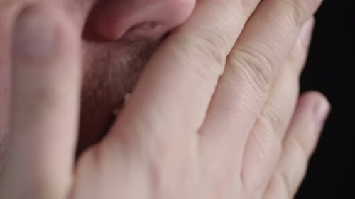 Close up: Bearded Caucasian man eats popcorn against black background
