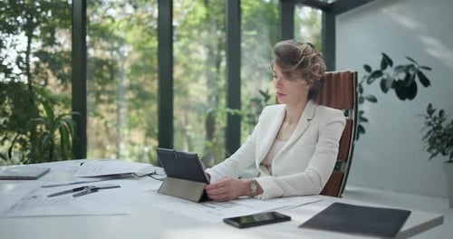 A Young Woman Architect Holding and Working with Tablet Pc Pad at Her Work Office with Big Sunlight
