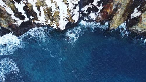 Flying Over Rocky Coastline Alongside Cliffside with Blue North Atlantic Ocean Water at Spring