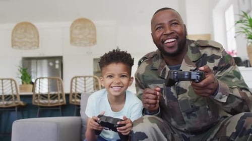 Smiling Father and Son Playing Video Games at Home