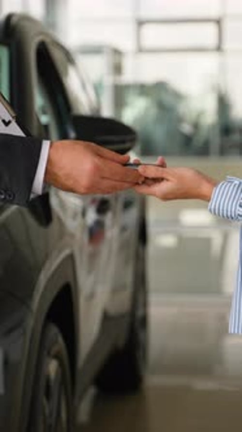 Salesman Giving Car Keys to Woman in Showroom