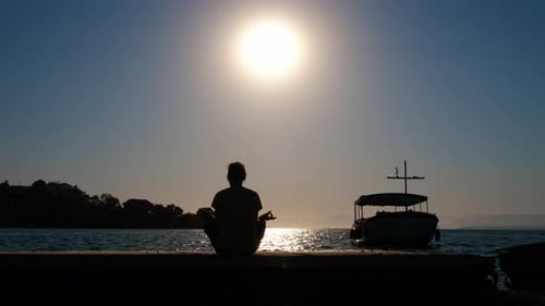 Meditating on Dock at Sunrise Over Ocean