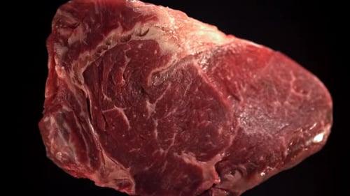 Beef Ribeye Steak fliegt hoch und fällt runter, gefilmt mit einer Hochgeschwindigkeitskamera mit 1000 Bildern pro Sekunde