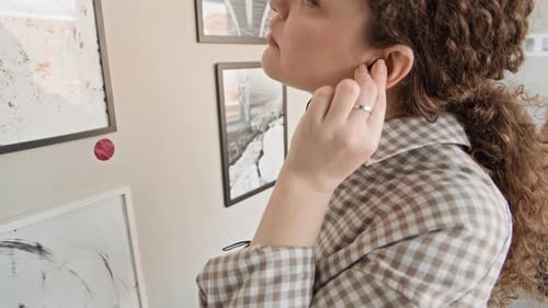 Junges Mädchen benutzt Audioguide beim Beobachten abstrakter Kunstmalerei in der Galerie