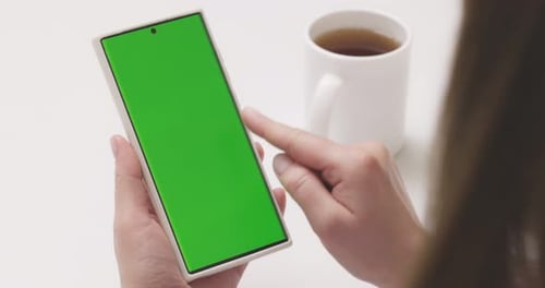 Woman with Green Screen Smartphone Scrolling Through Social Media or Online Shop