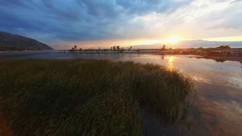 Panning over a still freshwater lake to sunset. showing a perfect reflection of the clouds and sun.