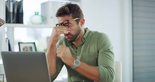 Frustrated Man Rubbing Eyes at Desk