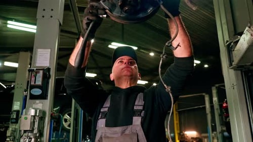 Closeup of a Car Mechanic at a Service Station Removing Disc From a Car