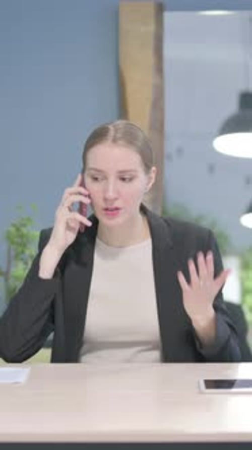 Woman in Blazer Talking on Phone at Desk