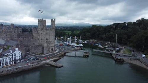 Ancient Caernarfon castle Welsh harbour town aerial view medieval waterfront landmark push in slow r