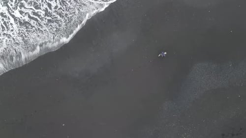 Lonely man walking on the beach of Iceland, Reynisdrangar, aerial