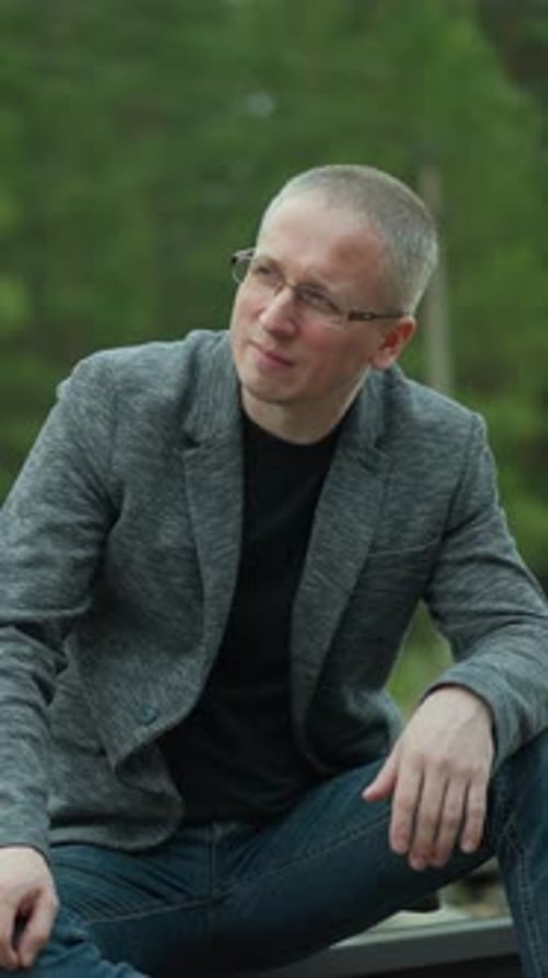 Man with Glasses Sitting on a Railway Track