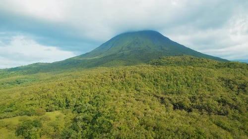 Wolkenbedeckter Gipfel des Vulkans Arenal, umgeben von grünem Wald in Costa Rica