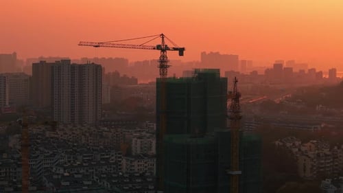 Orange Sky Over Construction Site During Sunset Buildings Under Construction with Cranes in the