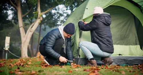Couple, camp and preparing a tent outdoor in nature with teamwork, tools and adventure