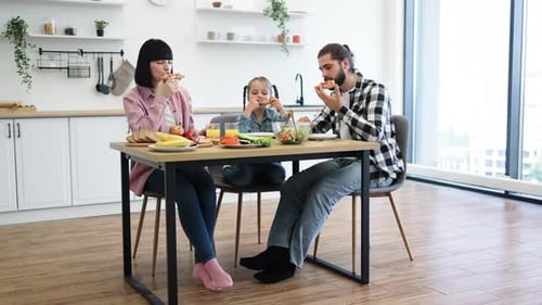 Family Eating Pizza at Kitchen Table Together