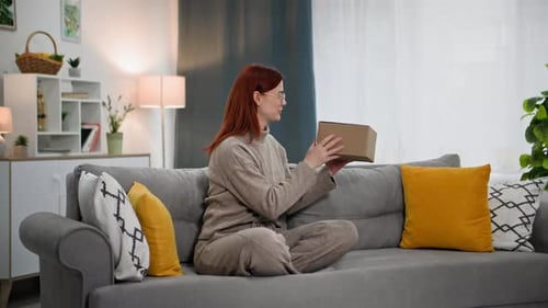 Gift Delivery Portrait of a Smiling Woman in Glasses Opens a Package From an Online Store Takes Out
