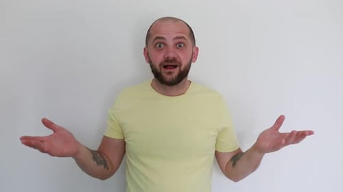 Excited Man in Yellow Shirt Expressing Surprise and Delight Against White Background