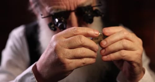 Senior man fixing mechanism of vintage wrist watch indoors, closeup. Camera moving in