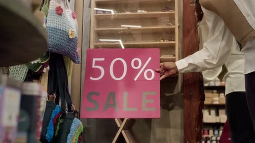 Female Worker Arranging Sale Sign in Store