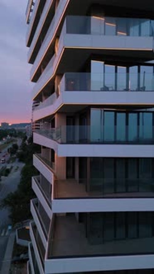 Modern Residential Building with Glass Balconies and LED Lighting at Sunset Urban Architecture and