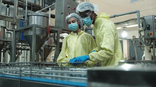 Deux superviseurs industriels examinent le contrôle de la qualité de la production d'aliments en conserve.