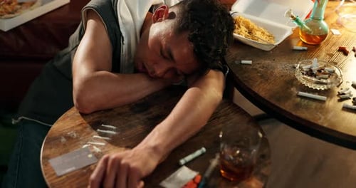 Young Adult Slumped at Table with Drugs