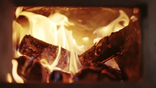 Close-up shot of wooden logs burning up in the traditional fireplace. Warm cosy fire.