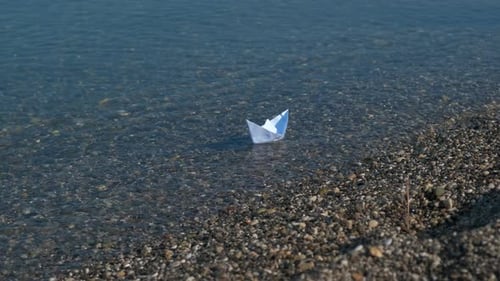 Paper Boat Floating in Clear Ocean Water