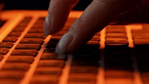 Close Up of Hands Typing on Keyboard in Dim Lighting