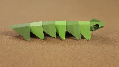 Paper worm made with the origami technique. Cork surface for crafts. Full shot.