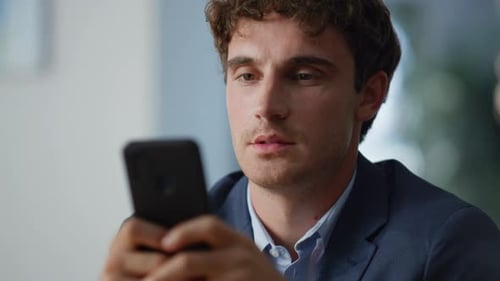 Relaxed Freelancer Browsing Cellphone Sitting Workplace at Work Break Closeup