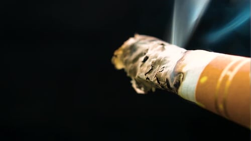 very tiny bit of a cigarette almost at the end of the filter burning clouds of smoke moving in all d