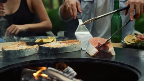 Grilled Salmon Cooking Over Open Fire Pit With Friends