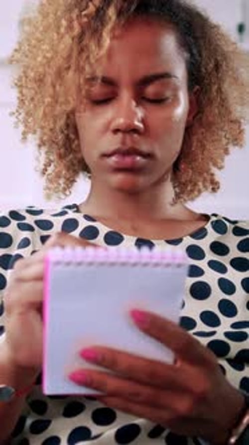 Young Woman Takes Notes While Concentrating in a Bright Room