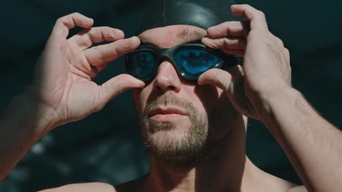 Portrait of Confident Caucasian Male Swimmer Putting on Goggles in Pool