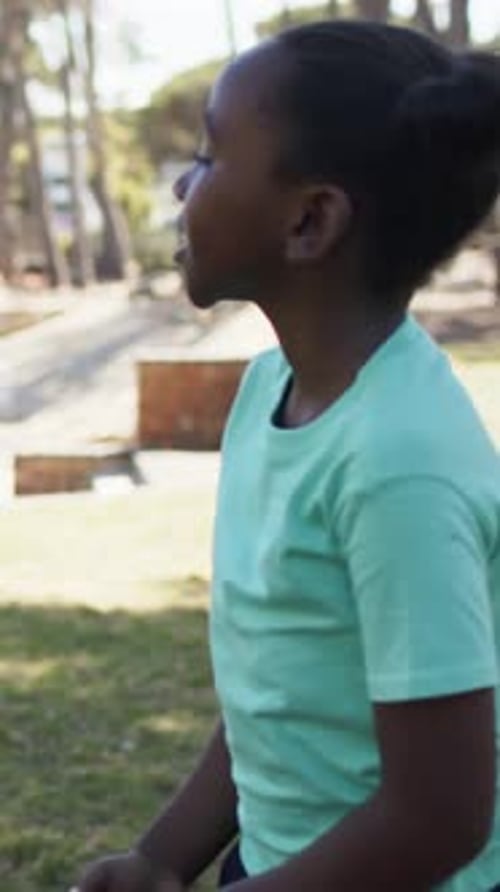 Menina adolescente com camisa de menta falando, estendendo a mão enquanto colega de equipe se aproxima, convidando a praticar esportes