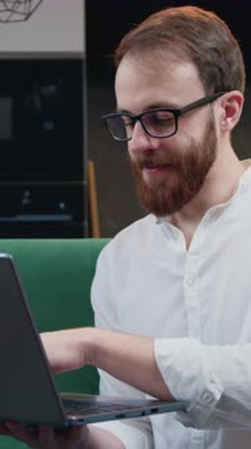 Attraktiver Mann, der sich mit Softwareentwicklung beschäftigt, arbeitet von zu Hause aus und konzentriert sich dabei auf den Laptop